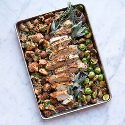 Baking pan filled with roasted turkey slices, vegetables and herbs